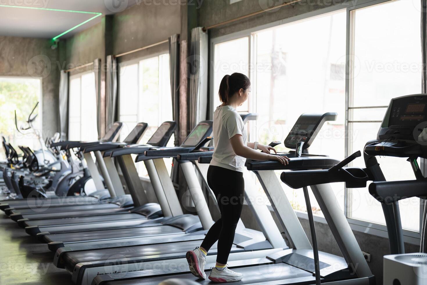 A woman is running on a treadmill in a gym photo