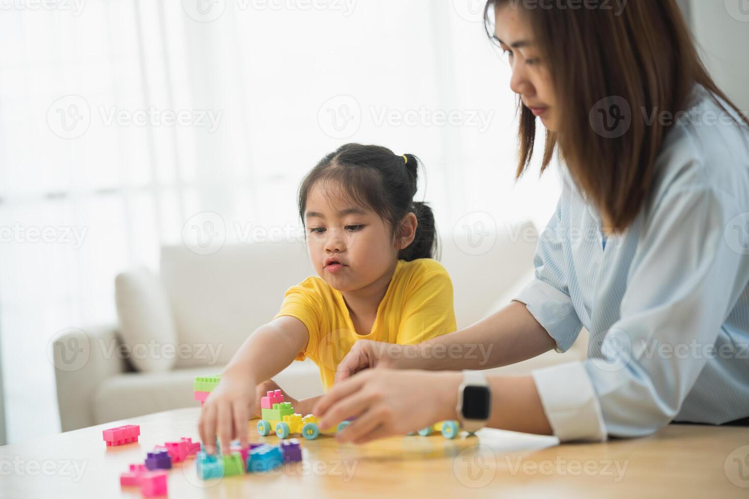 Asian woman and a child are playing with blocks. The woman is helping the child build a tower photo