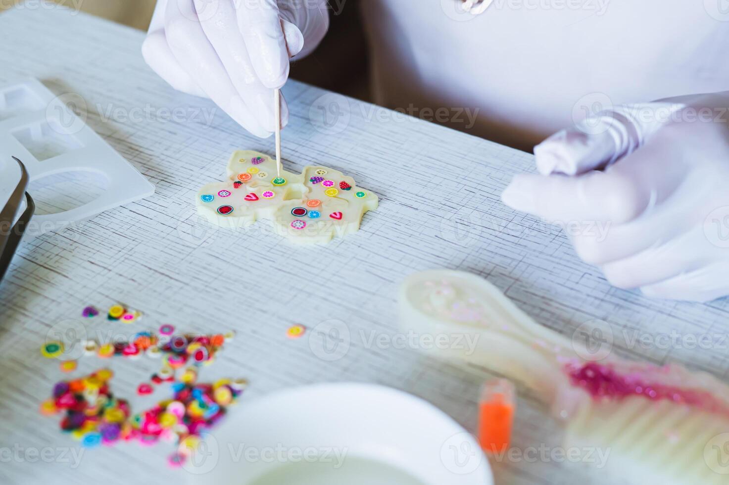 Female hands in gloves decorate earrings made of epoxy resin in the form photo