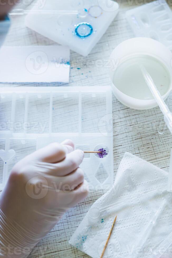 Children's hands in gloves fill a mold with glitter for an epoxy resin product photo