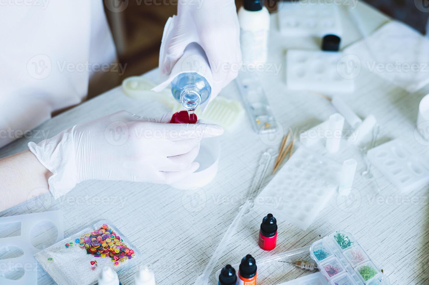 Female hands in gloves fill a measuring mold from a bottle with epoxy resin photo