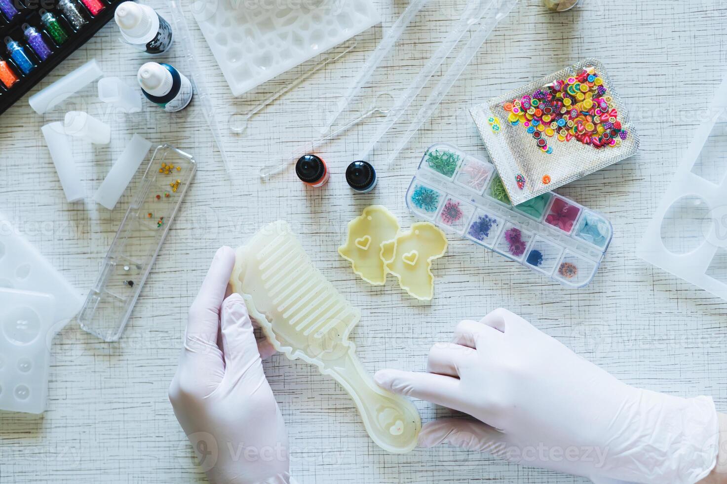 Female hands in gloves hold a mold for making a comb from epoxy resin photo
