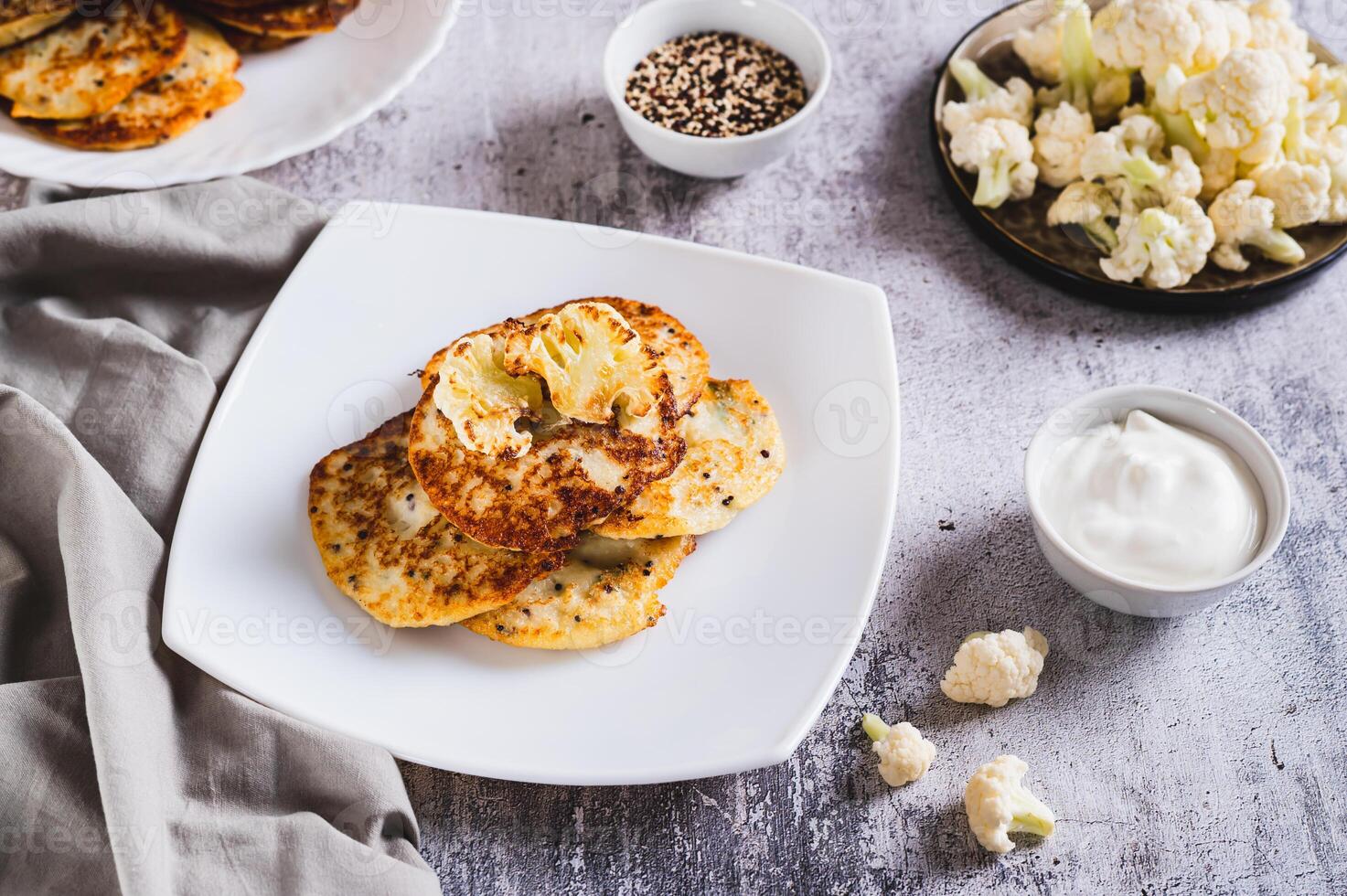 Homemade cauliflower fritters on a plate and sour cream in a bowl on the table photo