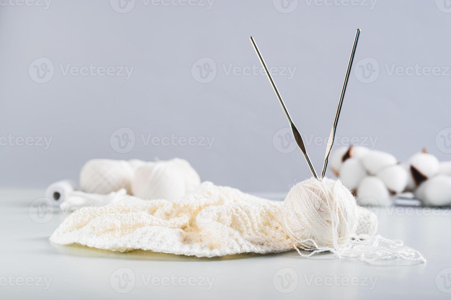 A ball of thread, hooks and an uncrocheted knitting on a blue table photo