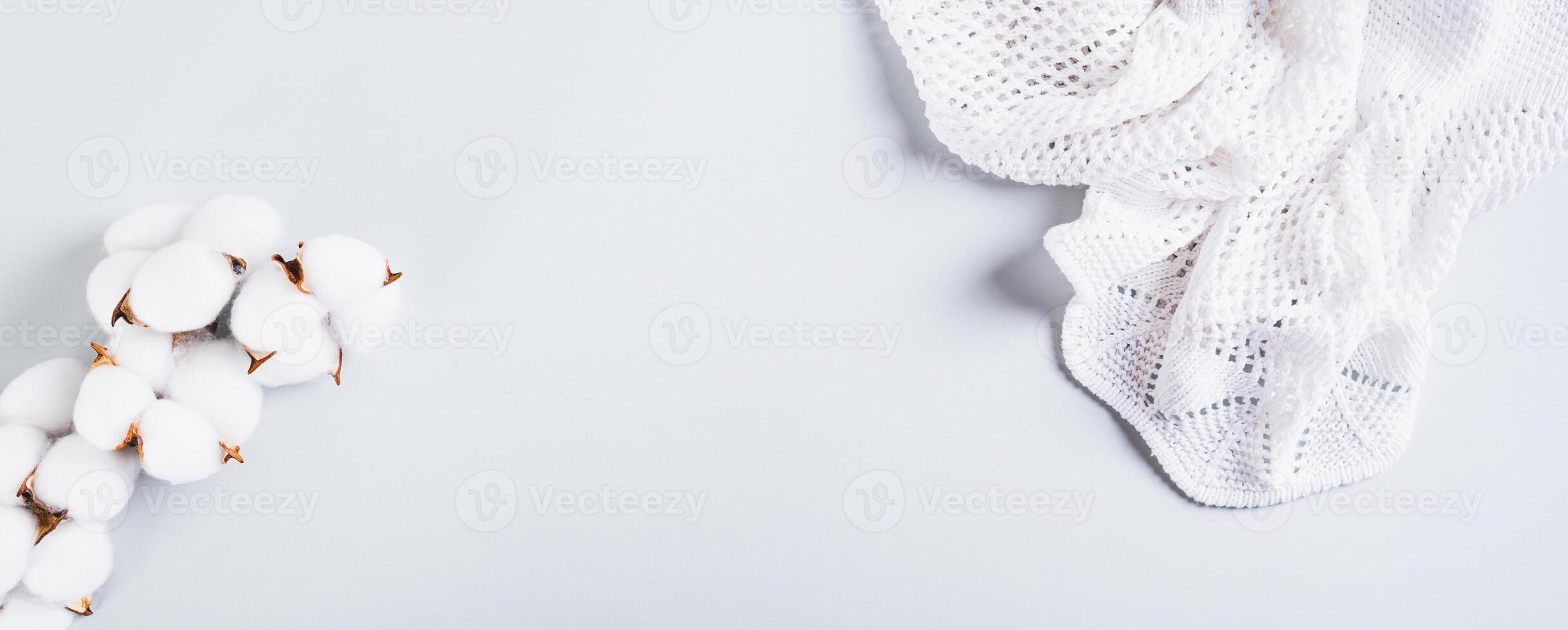 Texture knitted fabric and cotton branch on blue background web banner photo