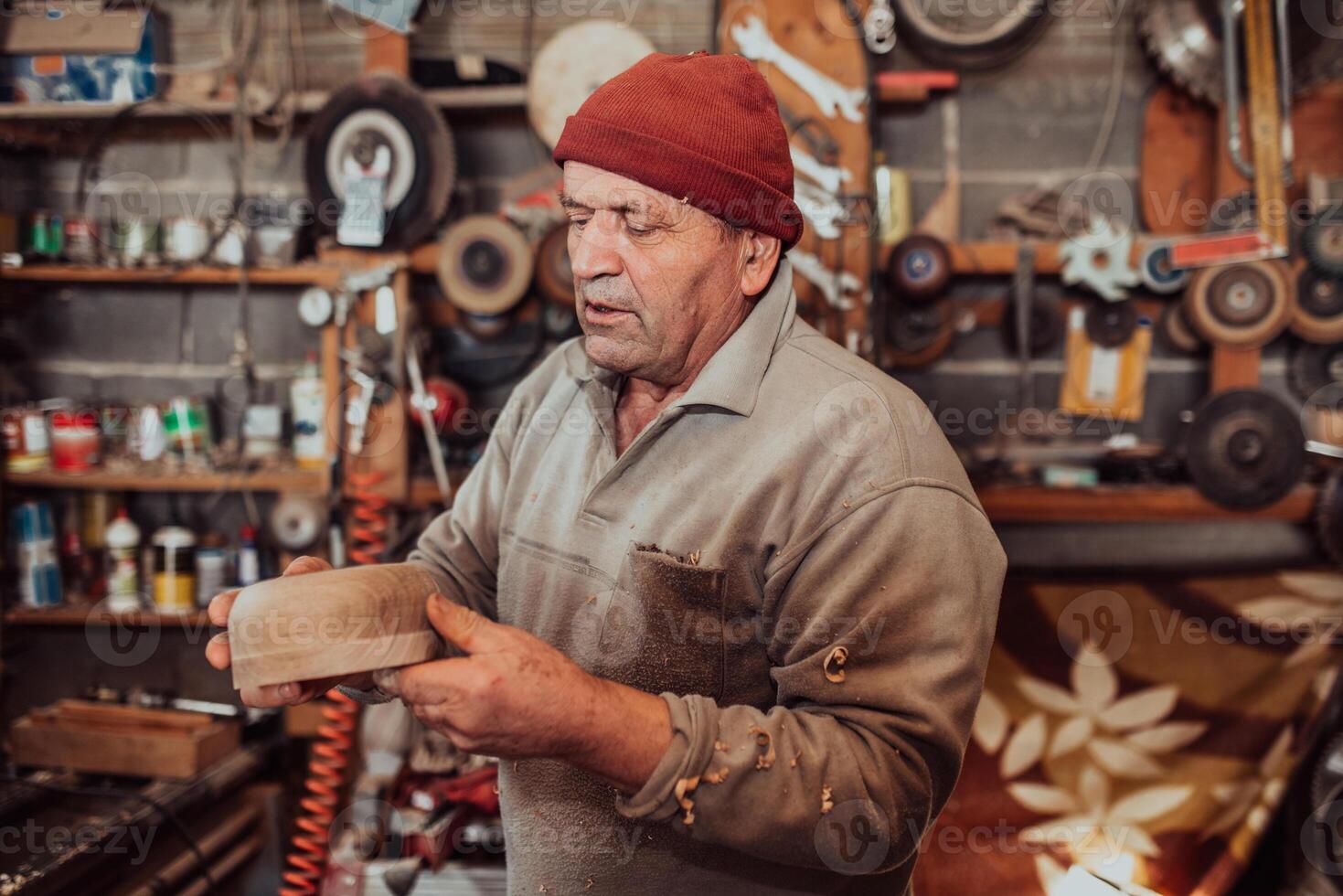 A senior man processing wooden dishes in the workshop in the traditional manual way photo