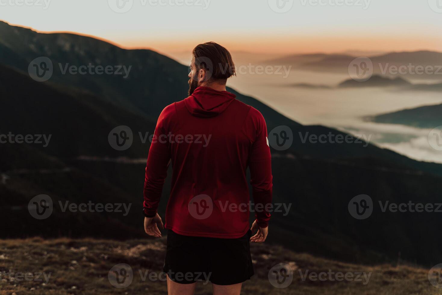 An athlete rests on top of a mountain after exhausting running training. photo