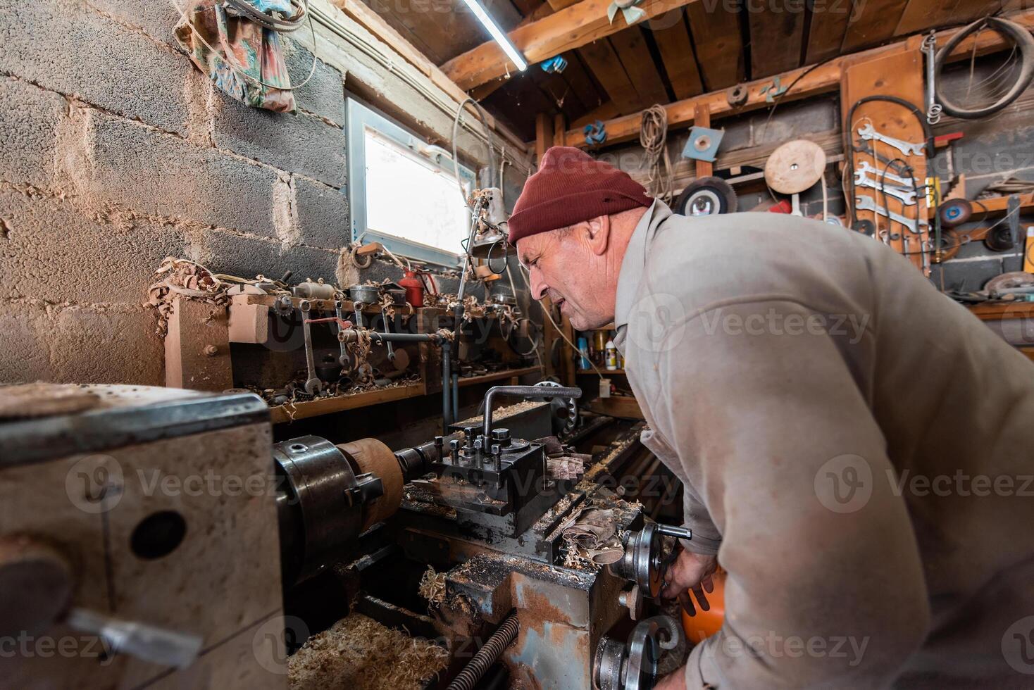 A senior man procesing wood on a lathe and making wooden dishes in the workshop photo