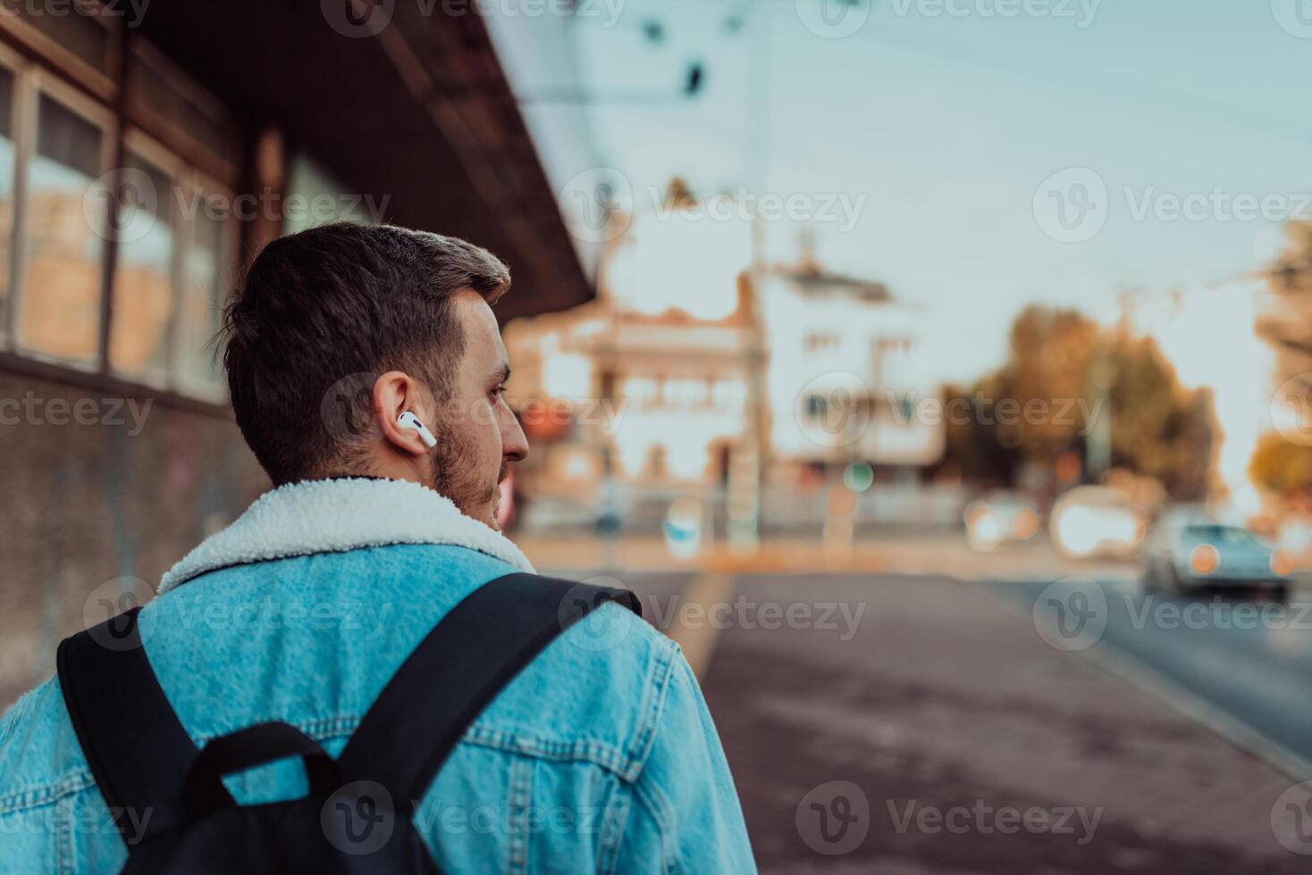 Back view of a man listening to music and talking on wireless headphones in the city center photo