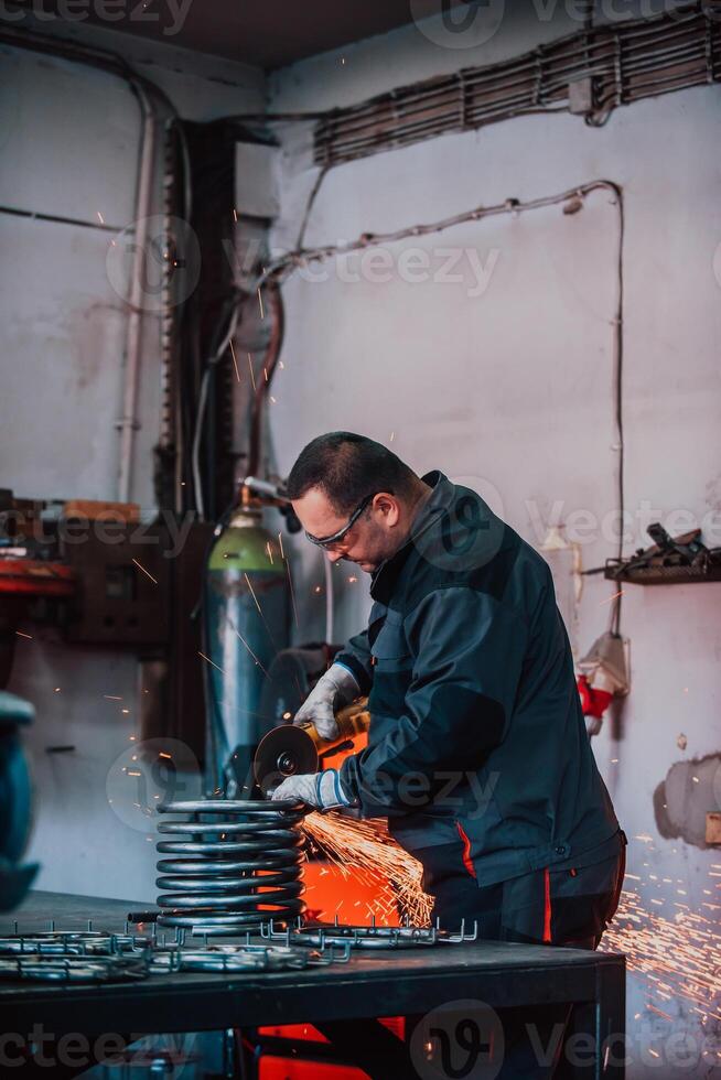 Locksmith in special clothes and goggles works in production. Metal processing with angle grinder. Sparks in metalworking. photo