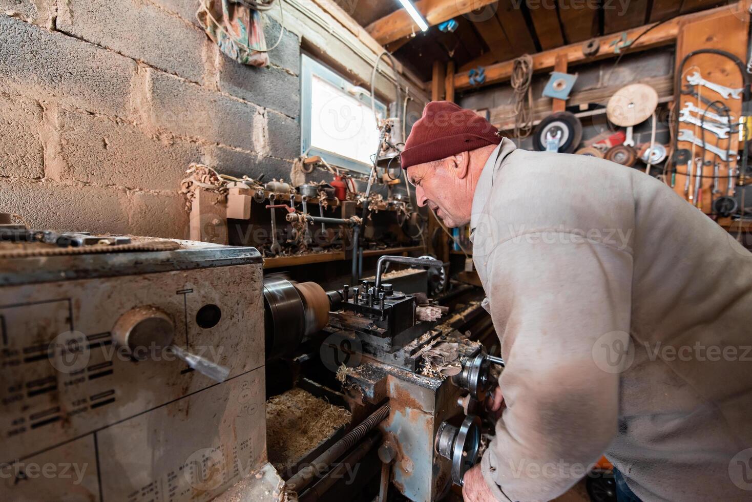 A senior man procesing wood on a lathe and making wooden dishes in the workshop photo