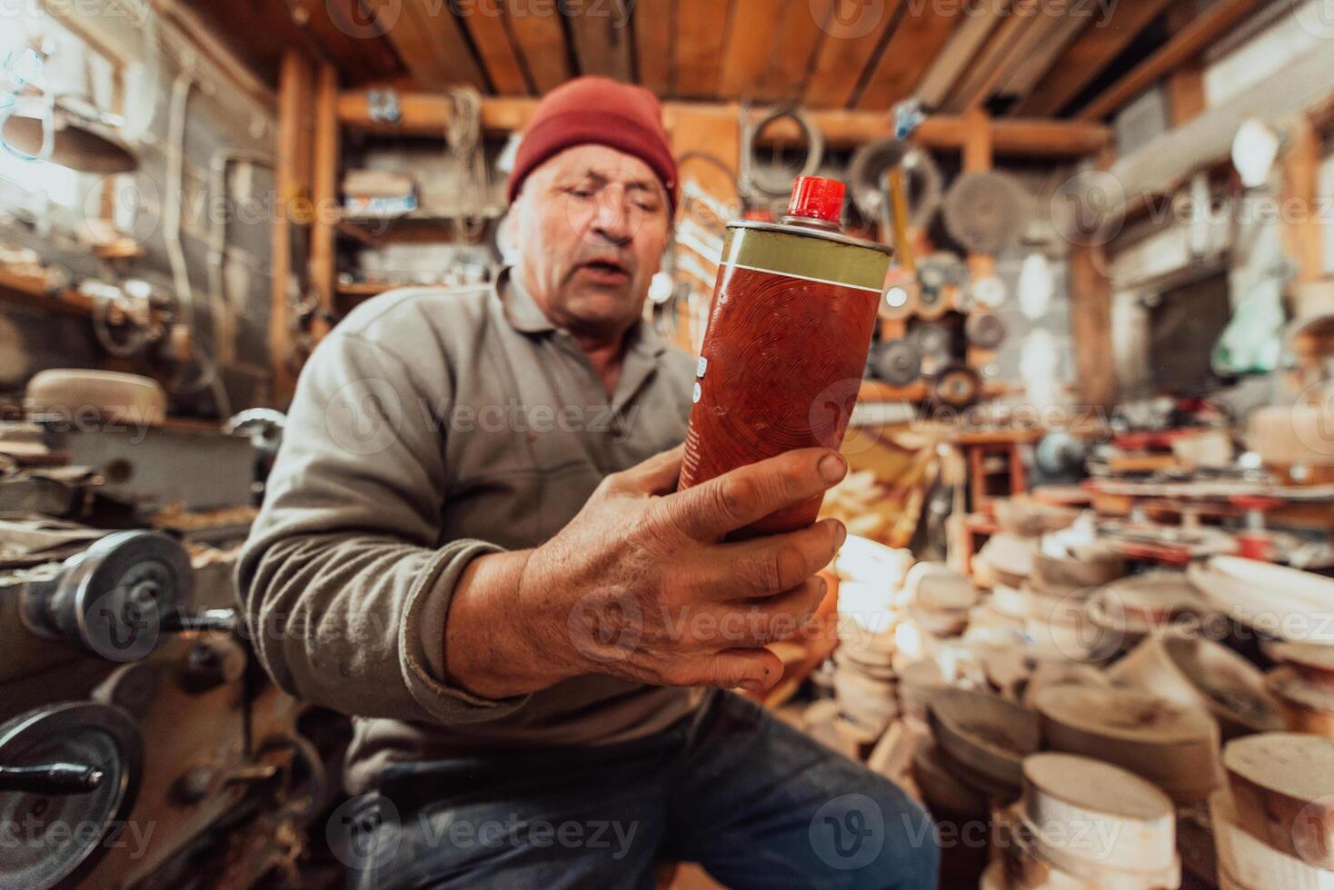 A senior man sitstingin the workshop and smearsing wooden utensils with linseed oil photo
