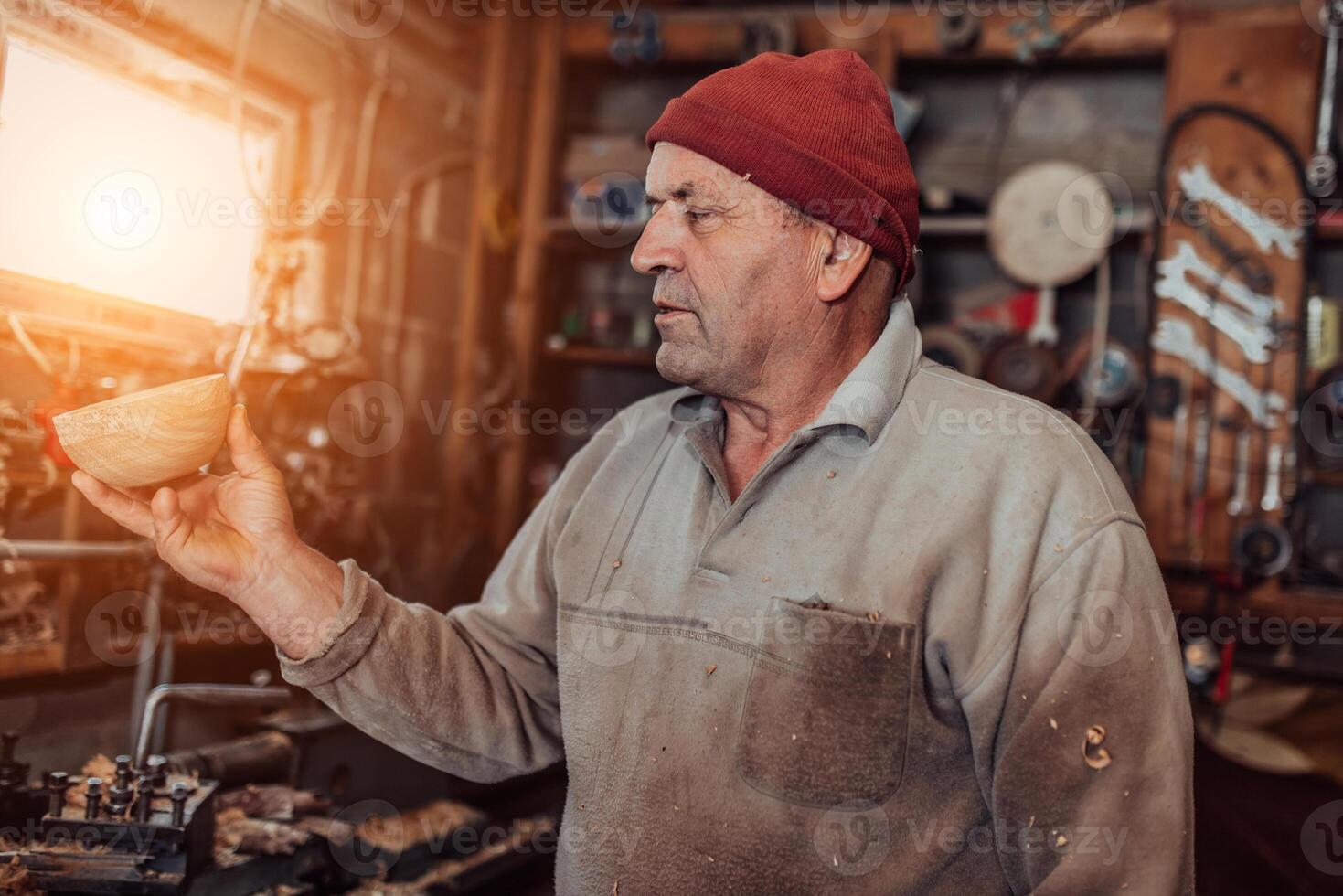 A senior man processing wooden dishes in the workshop in the traditional manual way photo