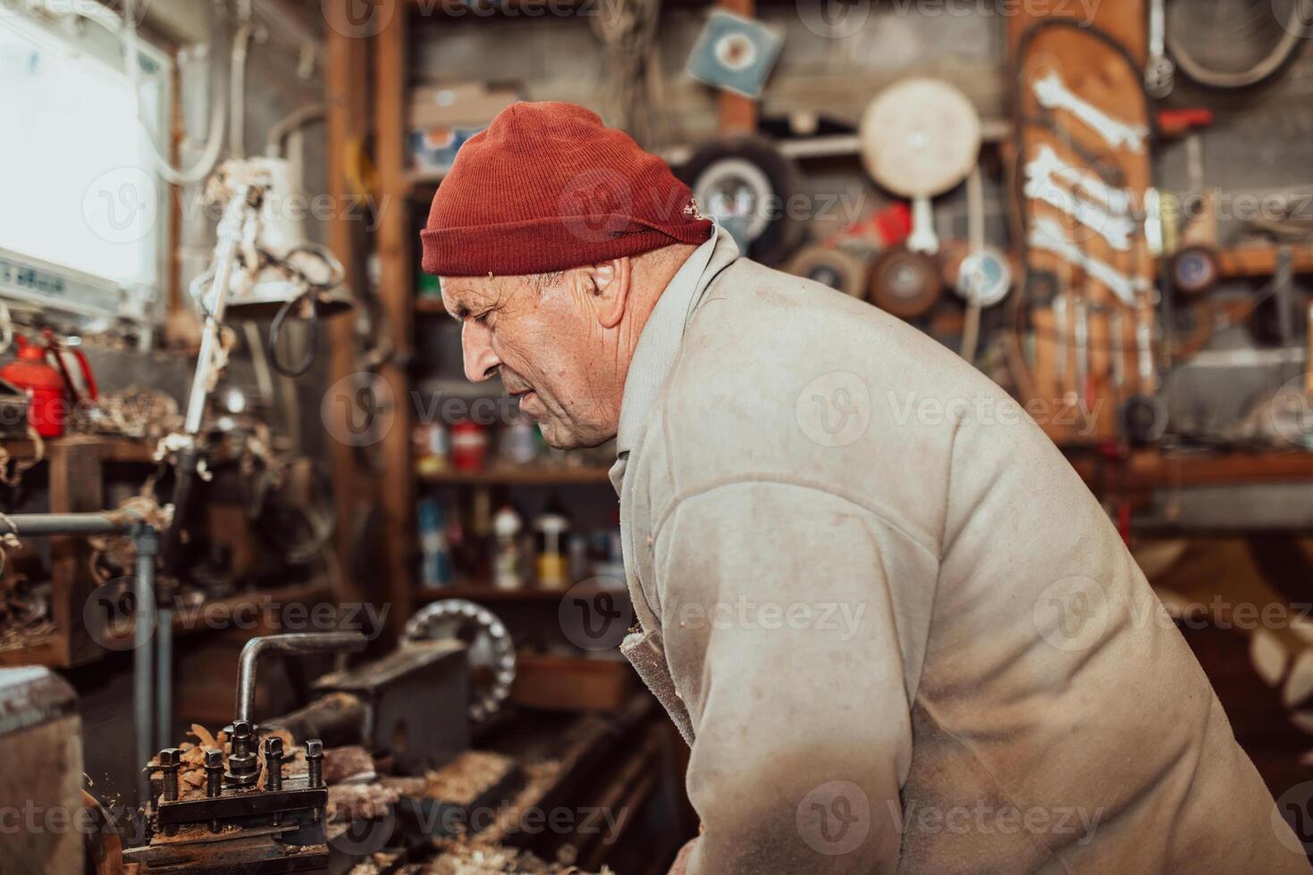 A senior man procesing wood on a lathe and making wooden dishes in the workshop photo