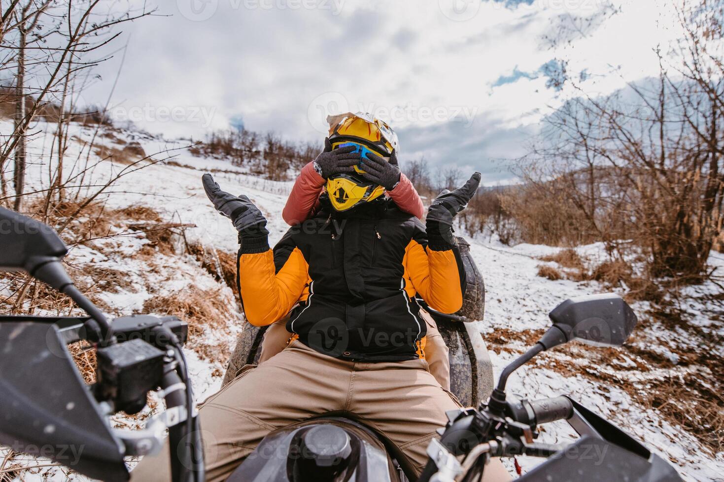 Couple enjoying while driving quad bike on top of mountain at winter time photo