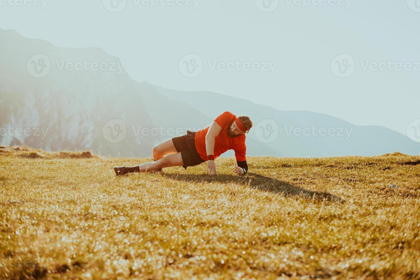 A man doing abs exercises on top of a mountain photo