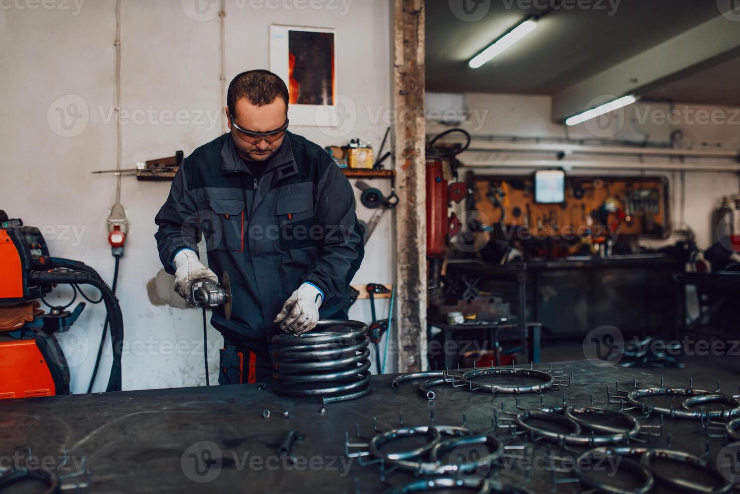 Locksmith in special clothes and goggles works in production. Metal processing with angle grinder. Sparks in metalworking. photo