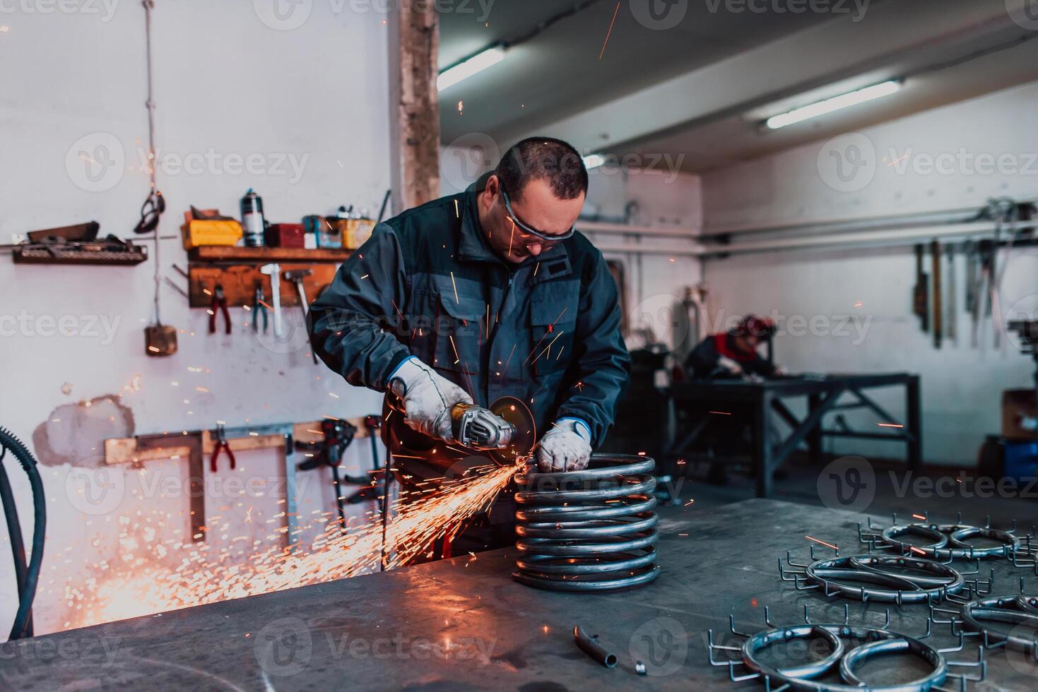 Locksmith in special clothes and goggles works in production. Metal processing with angle grinder. Sparks in metalworking. photo