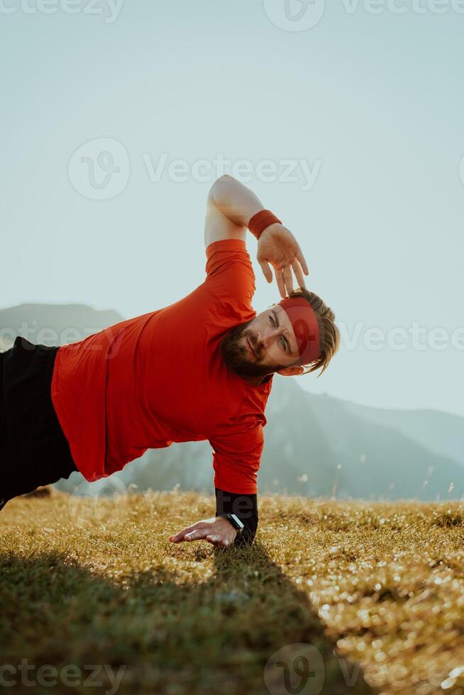 A man doing abs exercises on top of a mountain photo