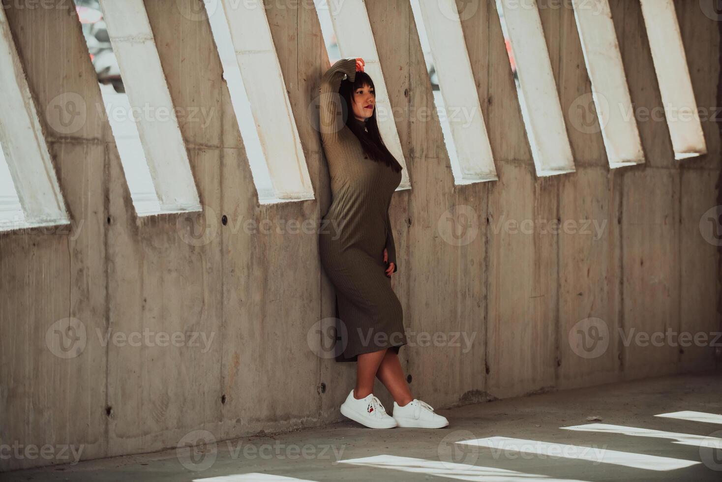 A confident and stylish plus-size woman posing by a modern building in an olive green dress, radiating beauty, empowerment, and self-love. photo