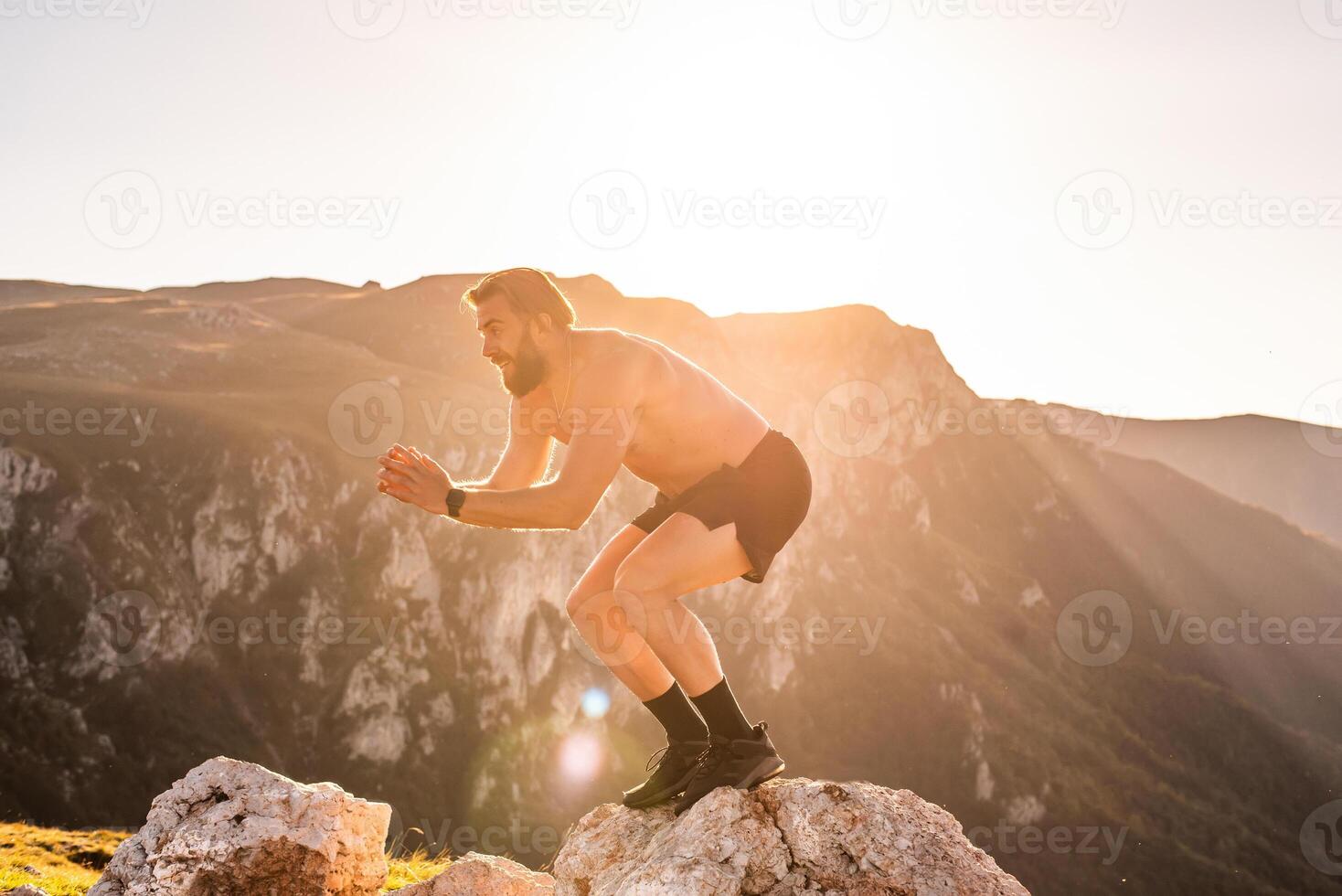 Man doing conditioning training on top of a mountain in the early morning with the sunrise in the background photo