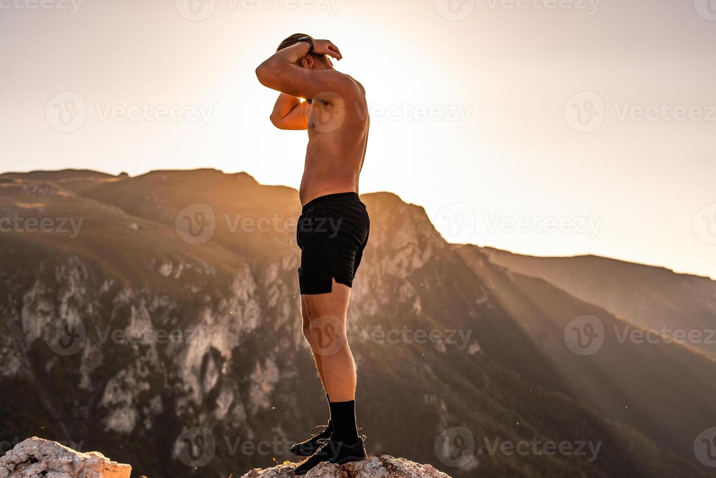 An athlete rests on top of a mountain after exhausting running training. photo