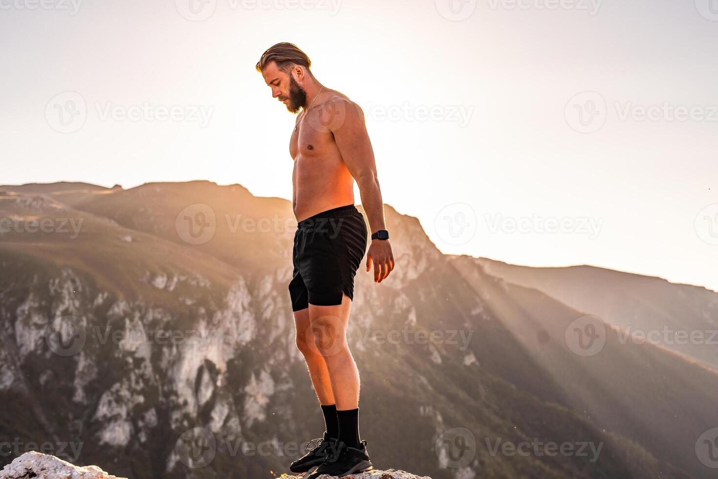 An athlete rests on top of a mountain after exhausting running training. photo