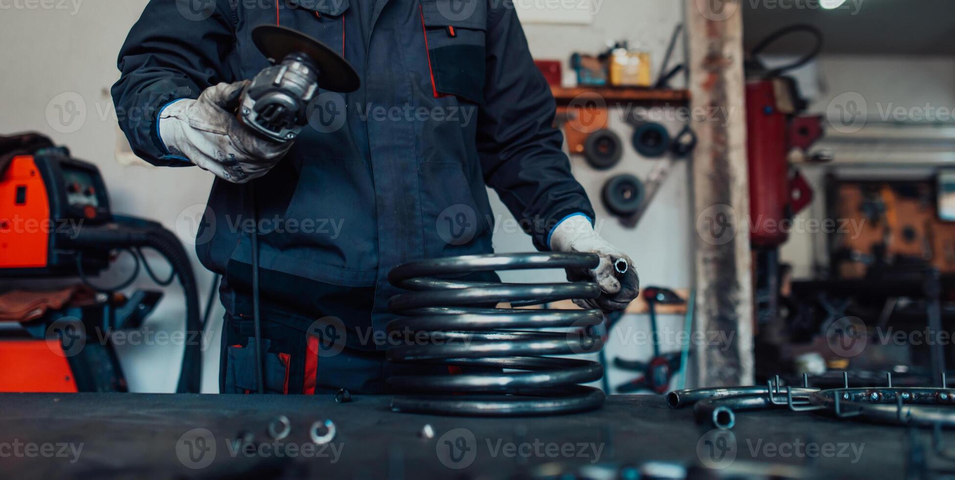 Locksmith in special clothes and goggles works in production. Metal processing with angle grinder. Sparks in metalworking. photo