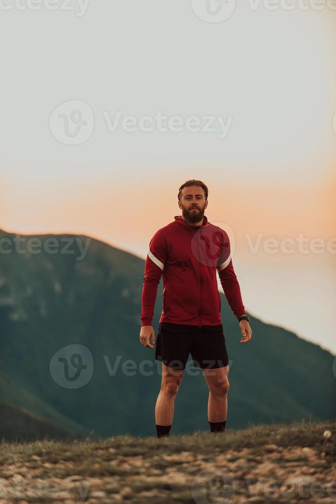 An athlete rests on top of a mountain after exhausting running training. photo