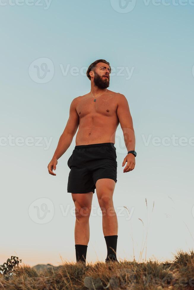 An athlete rests on top of a mountain after exhausting running training. photo
