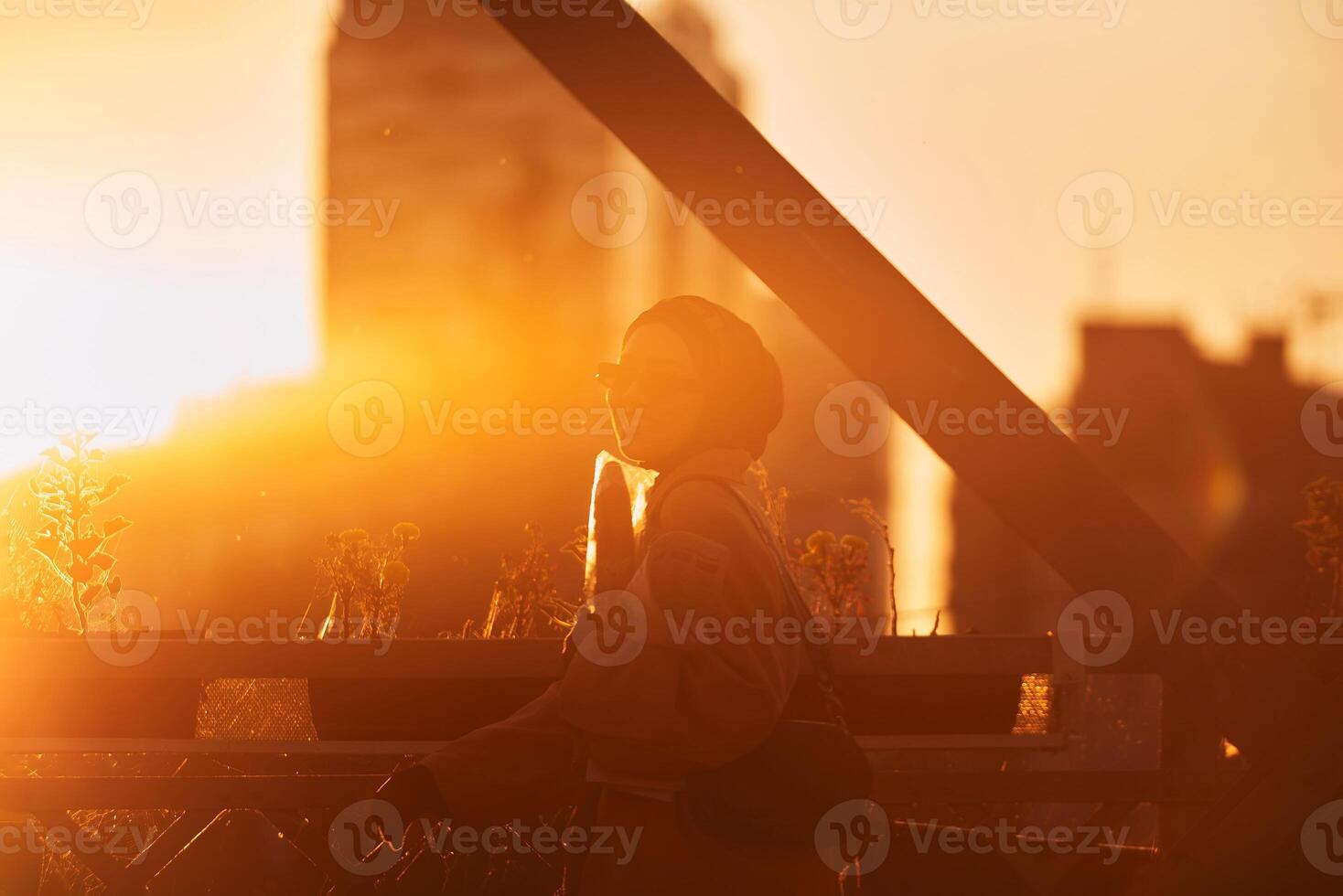 A hijab woman in stylish sunglasses and an elegant French outfit, walking through the city at sunset, carrying a bouquet, bread, and newspaper, radiating a sense of cultural charm and serenity photo