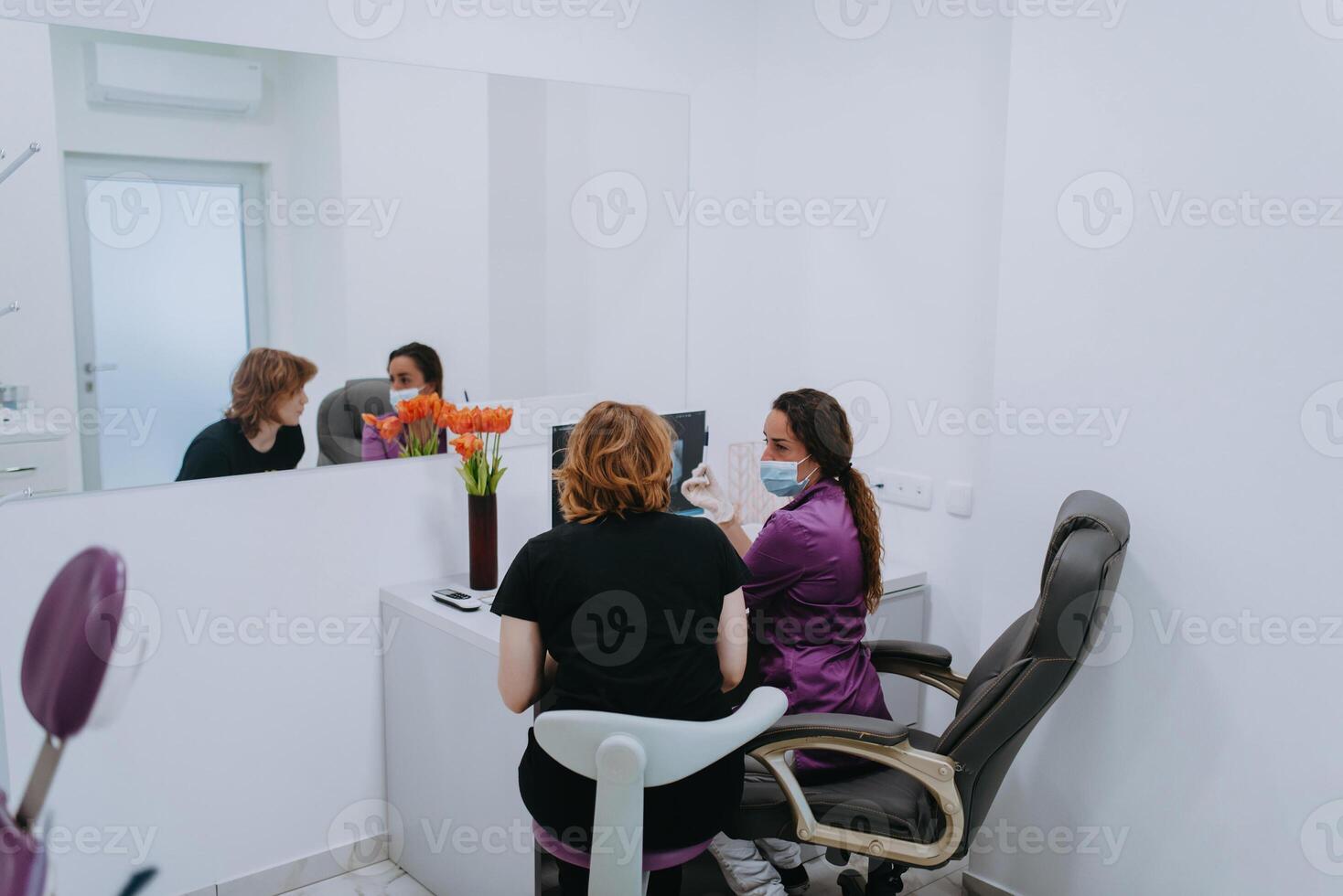 In a modern dental office, a dentist and a young patient engage in a collaborative consultation, exploring new tooth shades and discussing treatment options using a computer photo