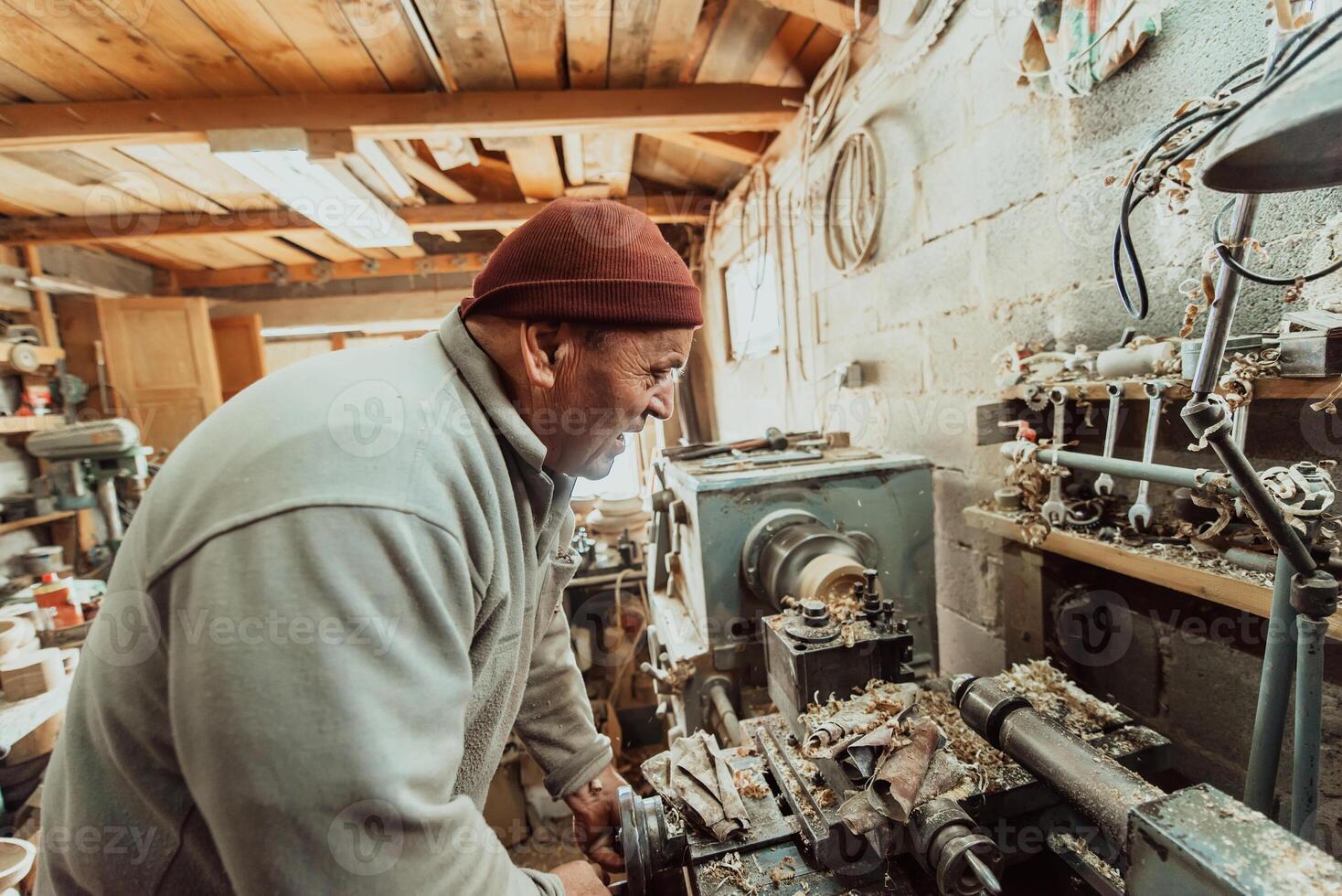 A senior man procesing wood on a lathe and making wooden dishes in the workshop photo