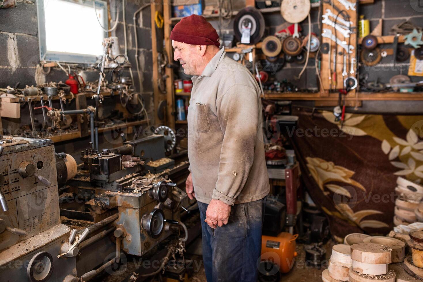 A senior man procesing wood on a lathe and making wooden dishes in the workshop photo