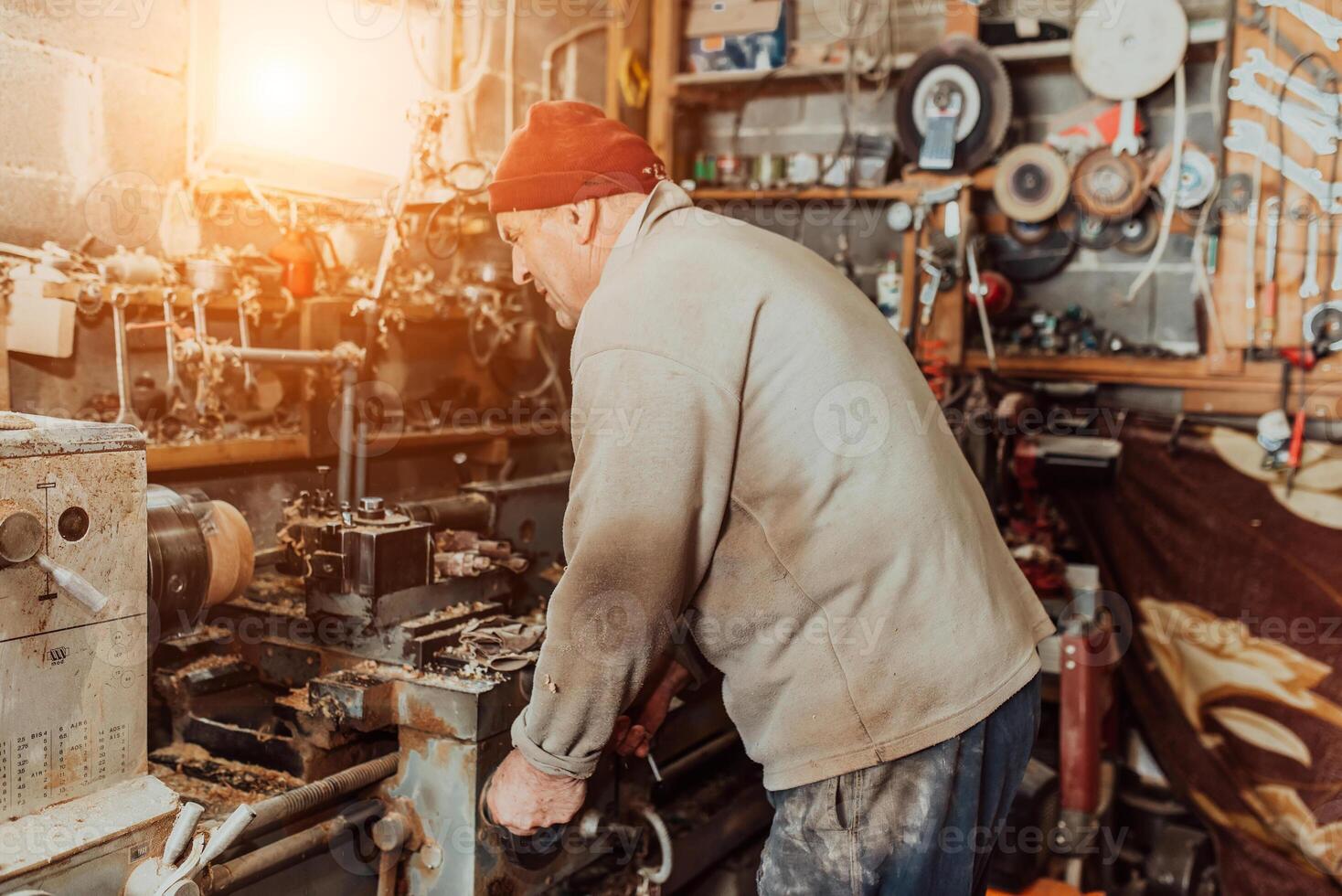 A senior man procesing wood on a lathe and making wooden dishes in the workshop photo