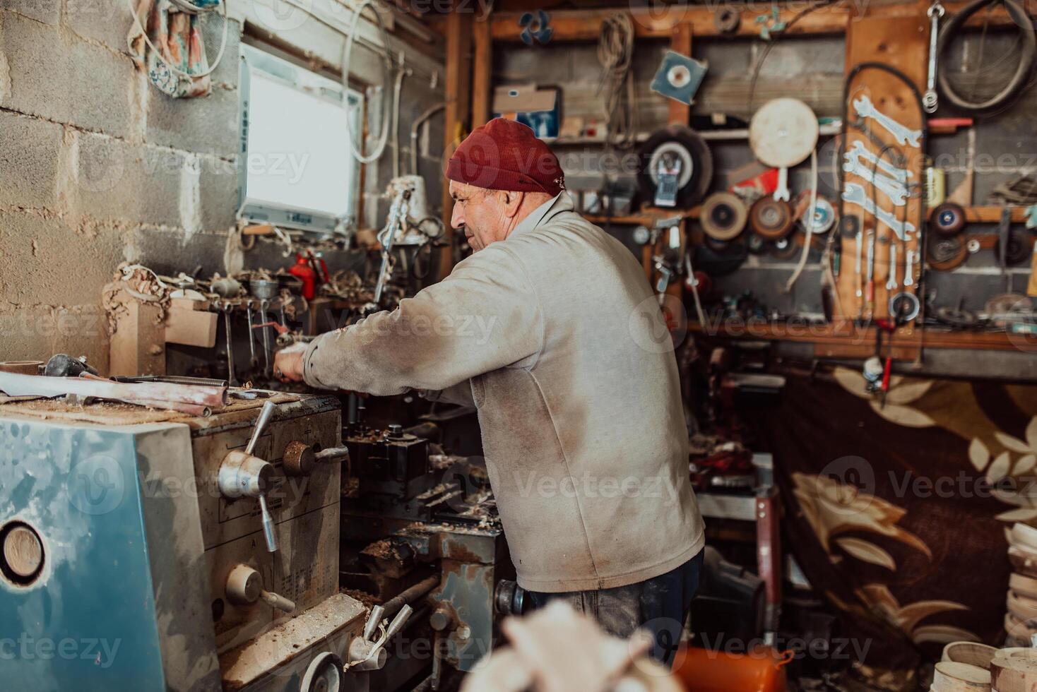 A senior man procesing wood on a lathe and making wooden dishes in the workshop photo
