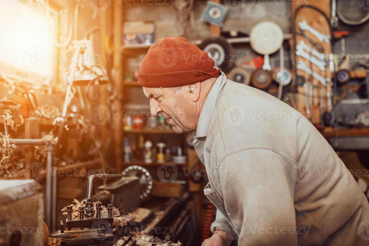 A senior man procesing wood on a lathe and making wooden dishes in the workshop photo