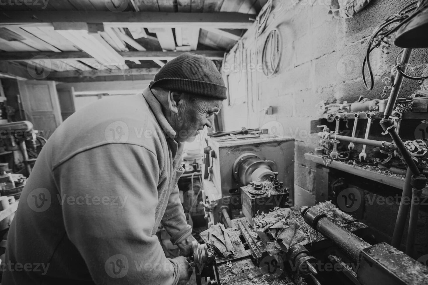 A senior man procesing wood on a lathe and making wooden dishes in the workshop photo