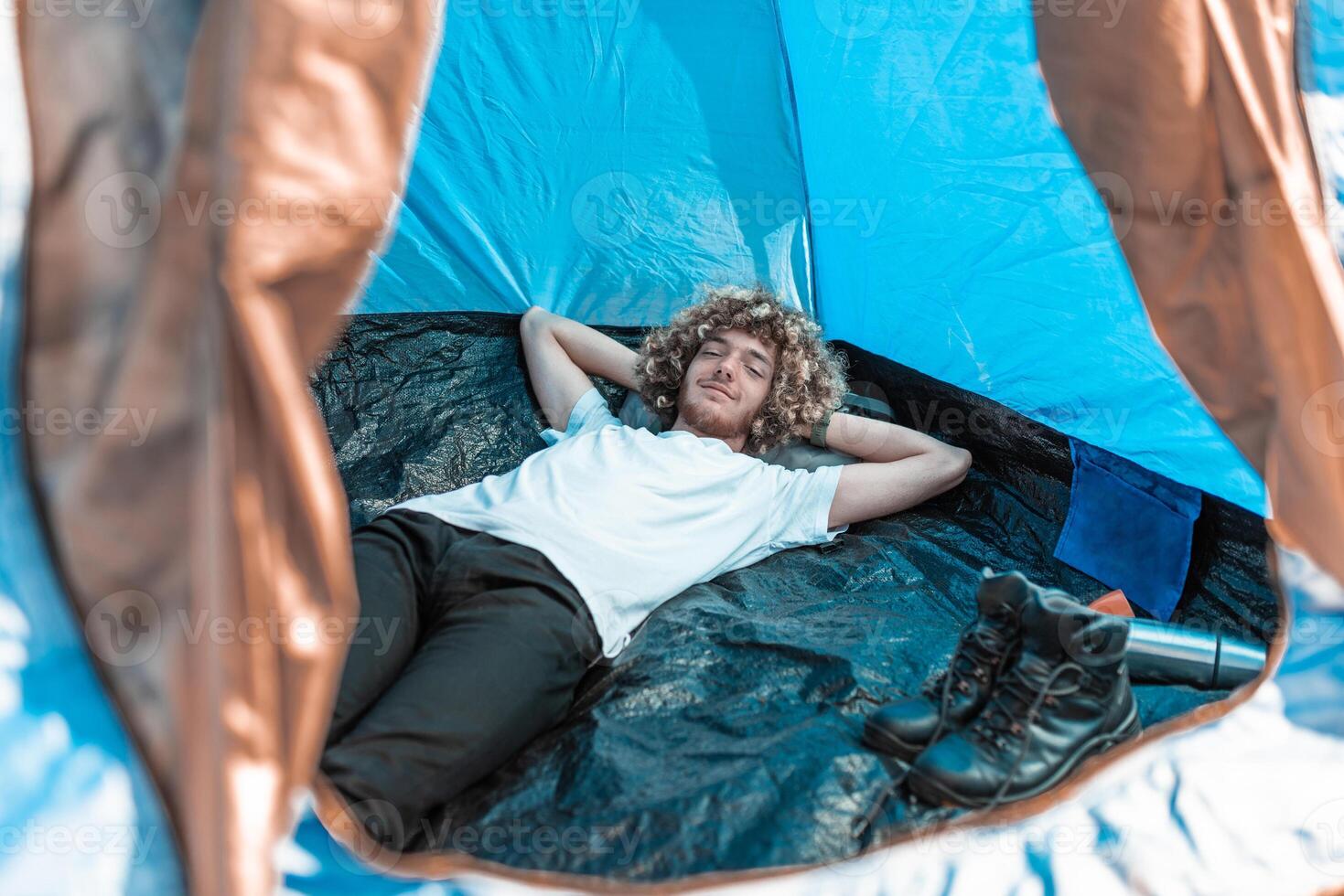 A mountaineer with an afro hairstyle li in a tent and rests from a hard hike photo