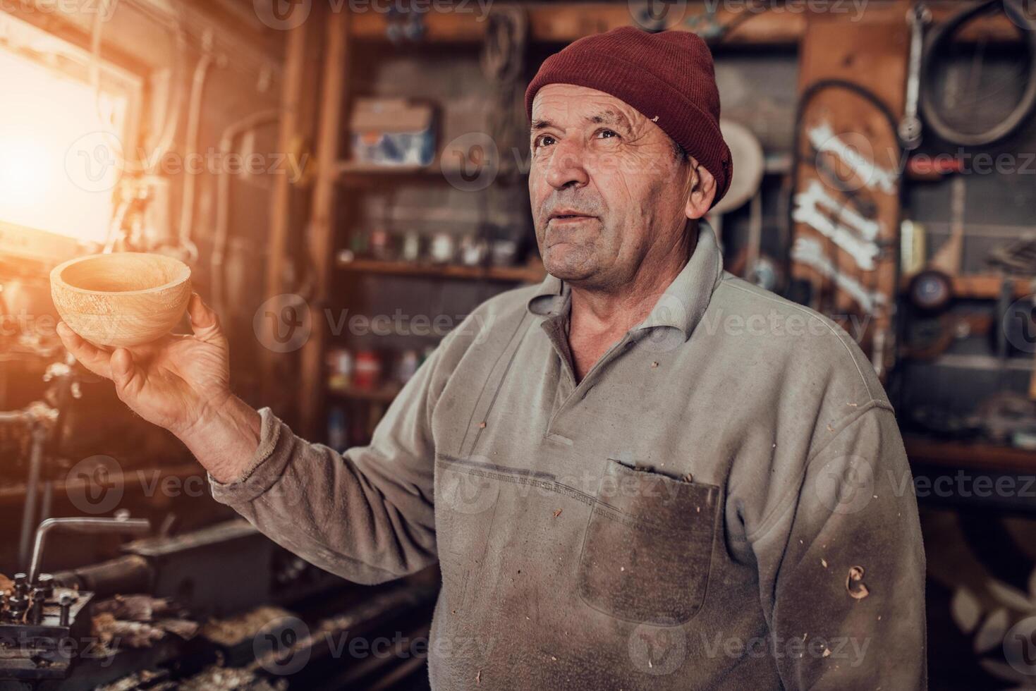 A senior man processing wooden dishes in the workshop in the traditional manual way photo