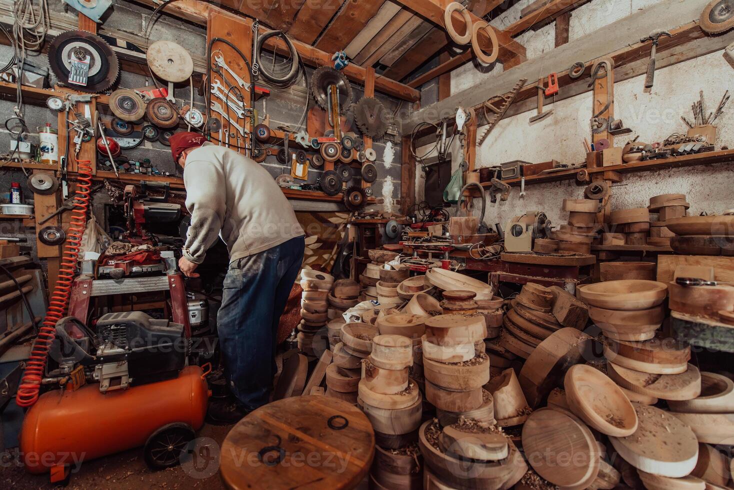 A senior man processing wooden dishes in the workshop in the traditional manual way photo