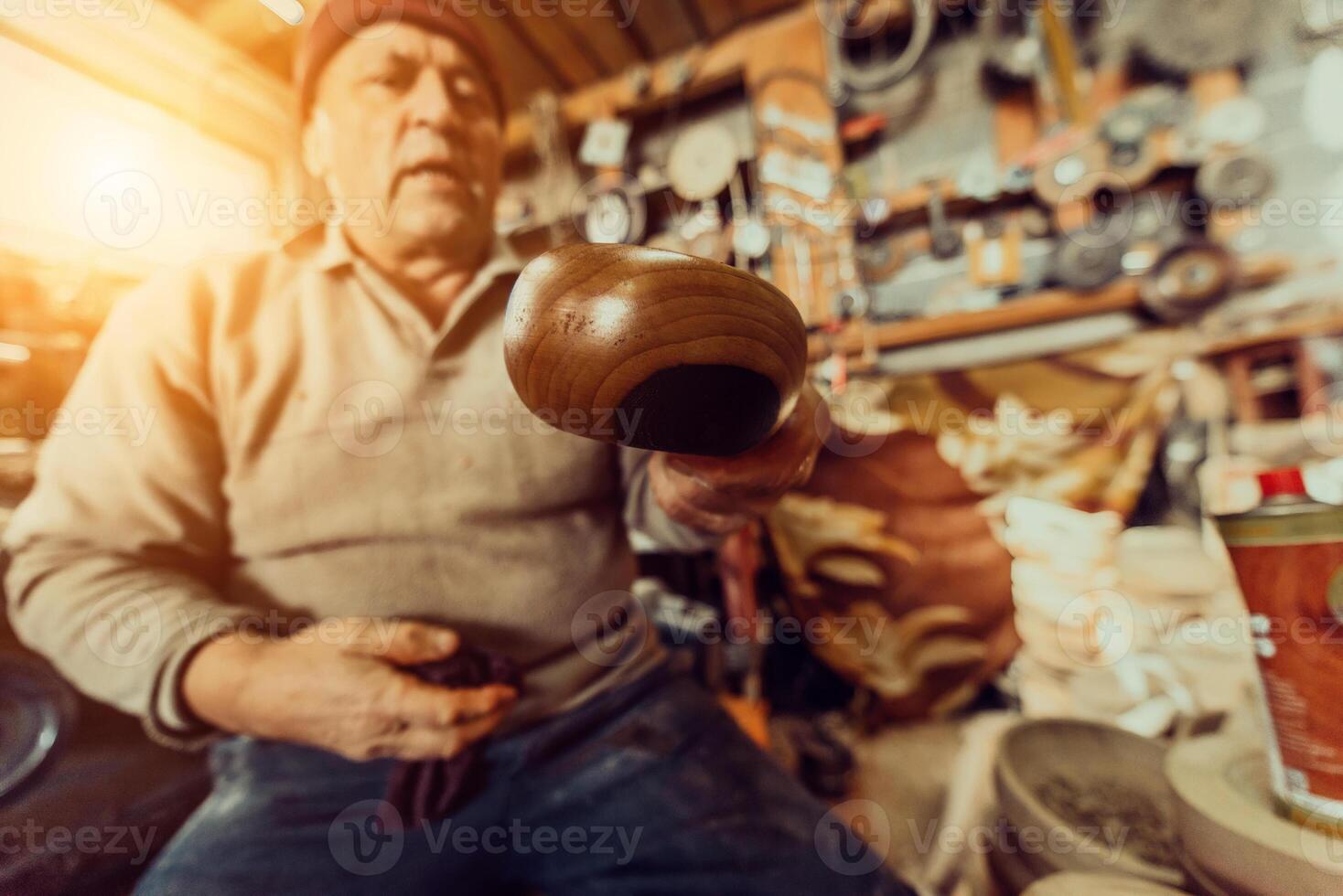A senior man sitstingin the workshop and smearsing wooden utensils with linseed oil photo
