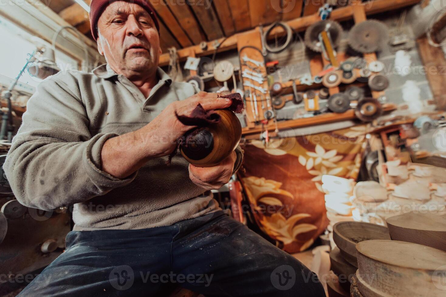 A senior man sitstingin the workshop and smearsing wooden utensils with linseed oil photo