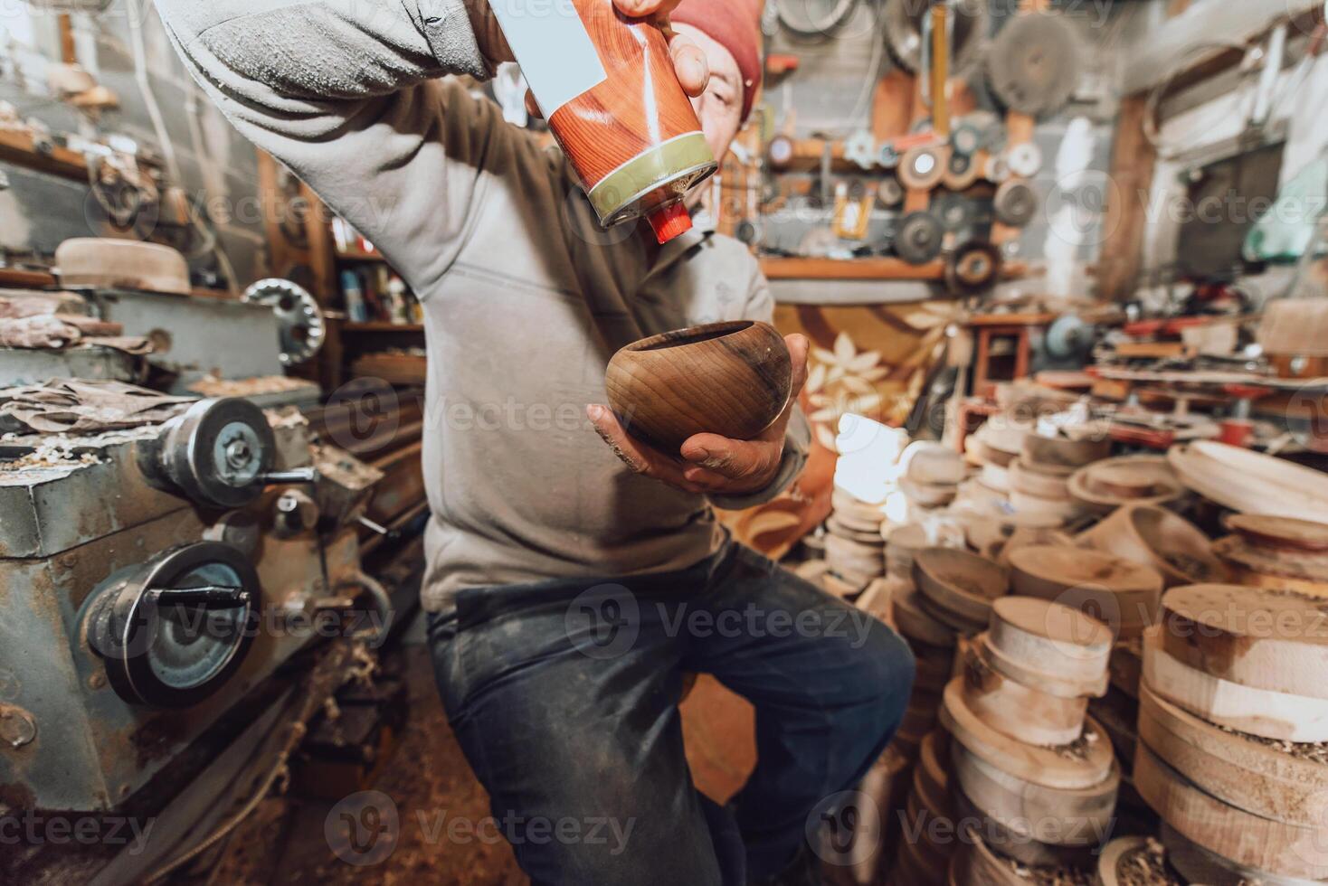 A senior man sitstingin the workshop and smearsing wooden utensils with linseed oil photo