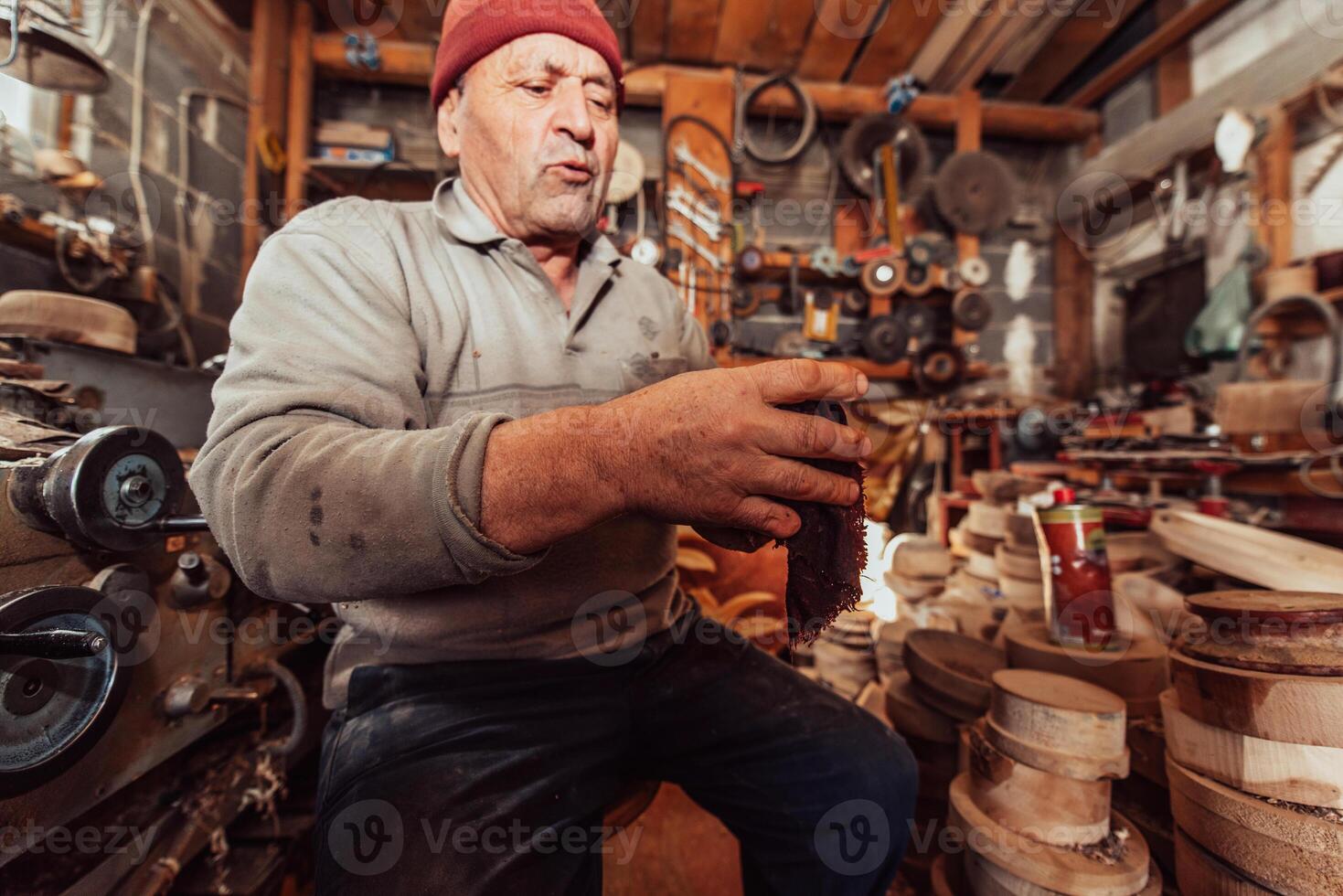 A senior man sitstingin the workshop and smearsing wooden utensils with linseed oil photo