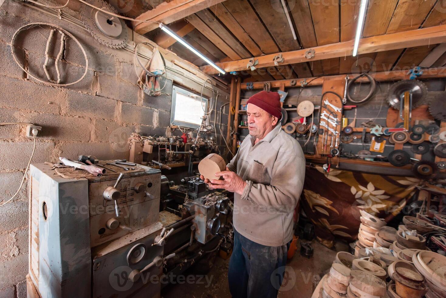 A senior man processing wooden dishes in the workshop in the traditional manual way photo