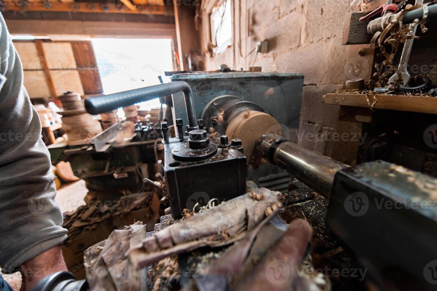 A senior man procesing wood on a lathe and making wooden dishes in the workshop photo