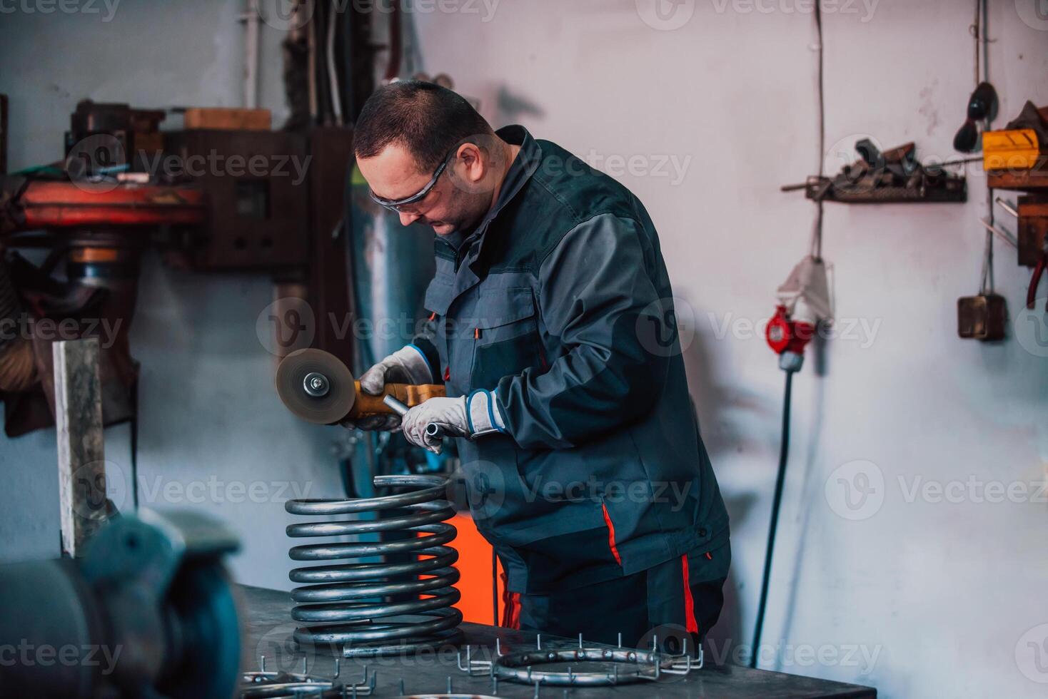 Locksmith in special clothes and goggles works in production. Metal processing with angle grinder. Sparks in metalworking. photo