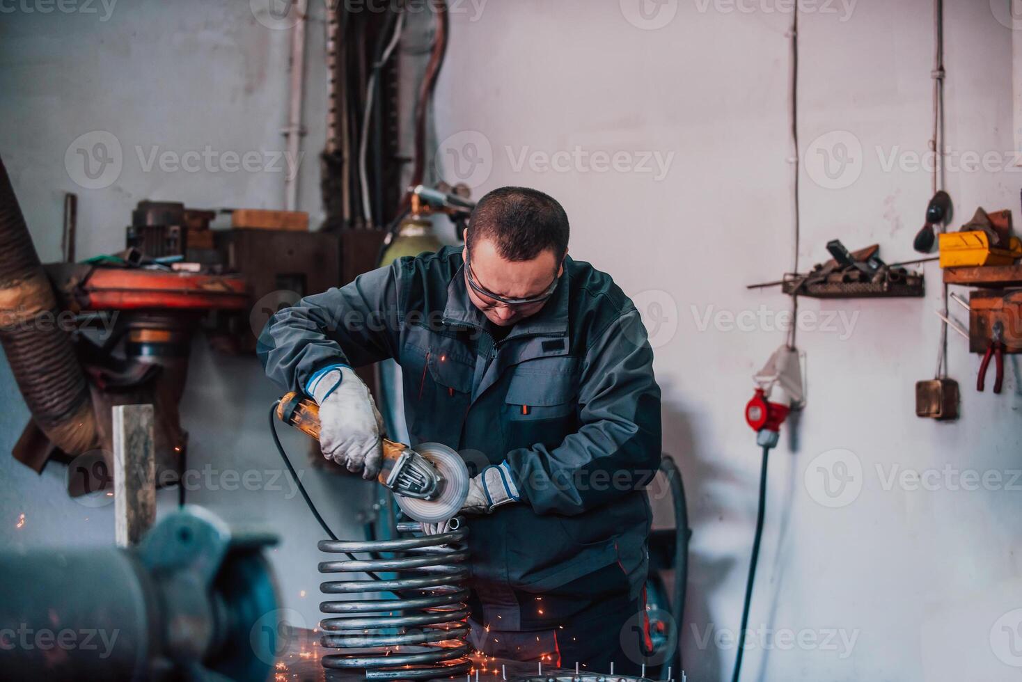 Locksmith in special clothes and goggles works in production. Metal processing with angle grinder. Sparks in metalworking. photo