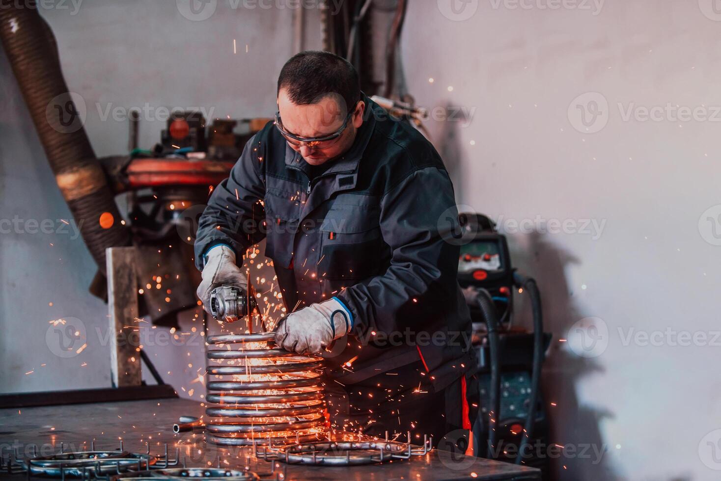 Locksmith in special clothes and goggles works in production. Metal processing with angle grinder. Sparks in metalworking. photo